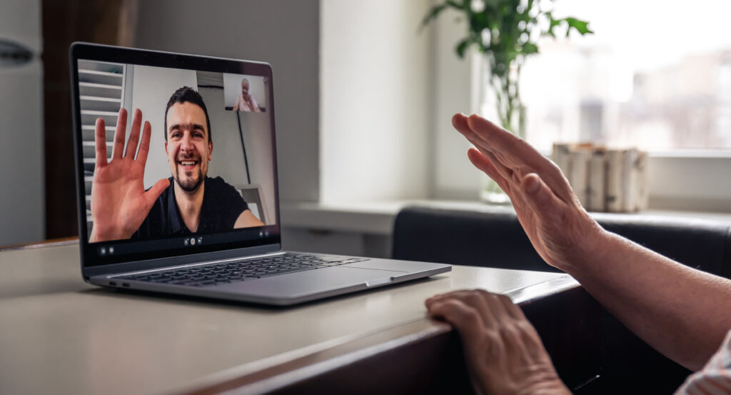 Persona saludando en una videollamada desde su notebook